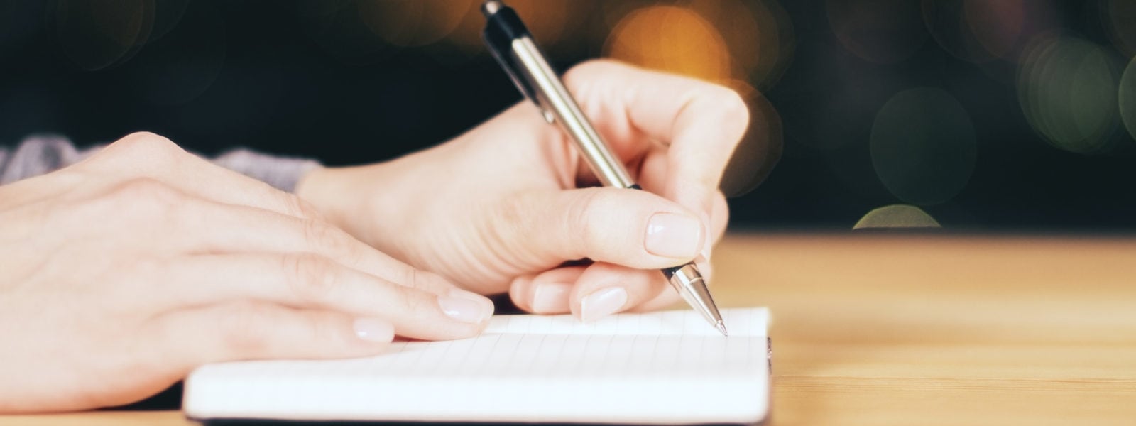 Girl writing in the diary on wooden table at night