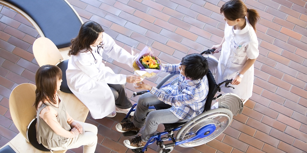 Doctor giving patient a bunch of flowers as he leaves hospital